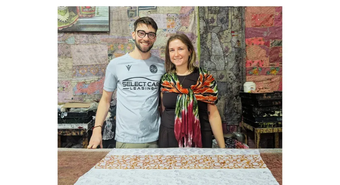 Eva with a traveller holding a block-printed fabric in a Jaipur atelier